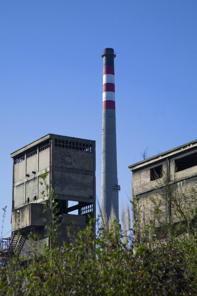 Instalaciones abandonadas de la Factoría de Nitrastur, con la chimenea de la Central Térmica al fondo. Langreo. Asturias 2016