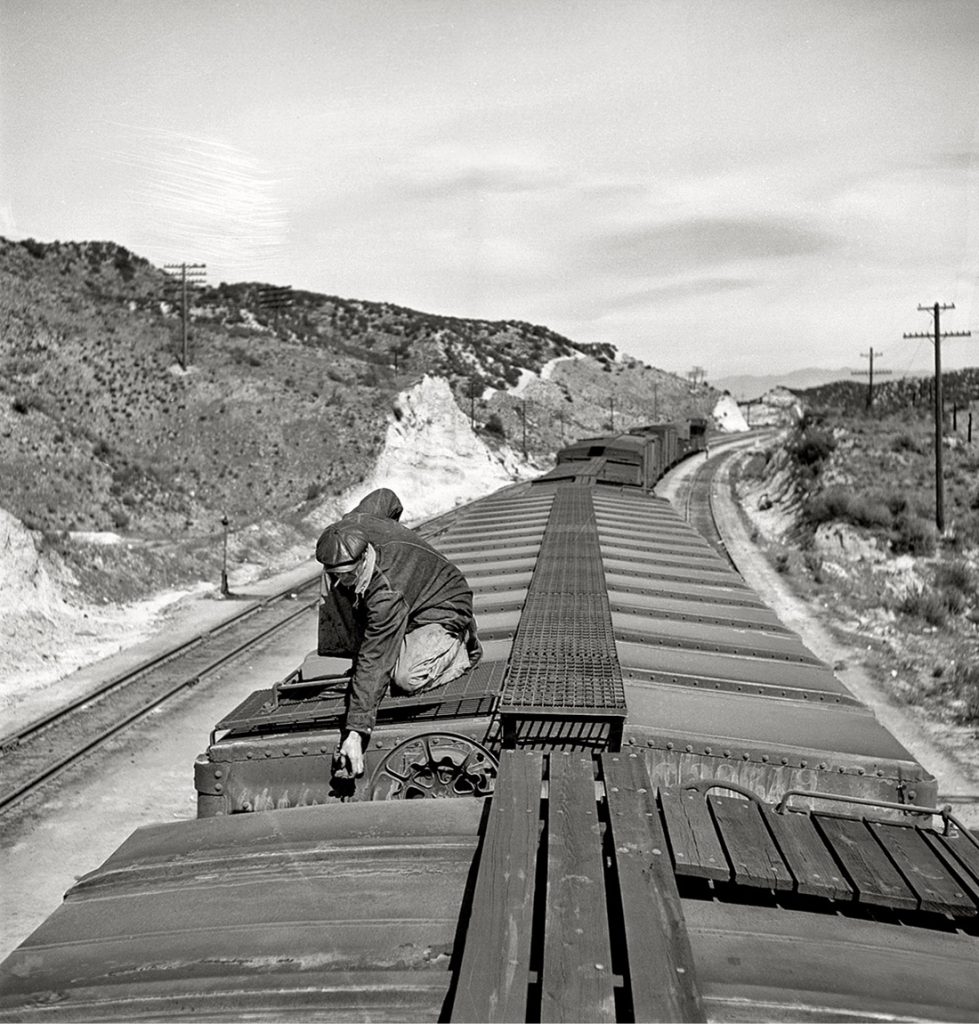 Guardafrenos abriendo la válvula de retención en un vagón en la linea de ferrocarril Atchison, Topeka y Santa Fe entre Barstow y San Bernardino. California. EEUU. 1943