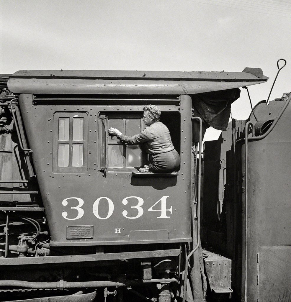 Mujeres limpiaparabrisas de la linea de ferrocarril del Noroeste de Chicago limpiando una de las locomotoras de carga gigante. Clinton, Iowa. EEUU. Año 1943.