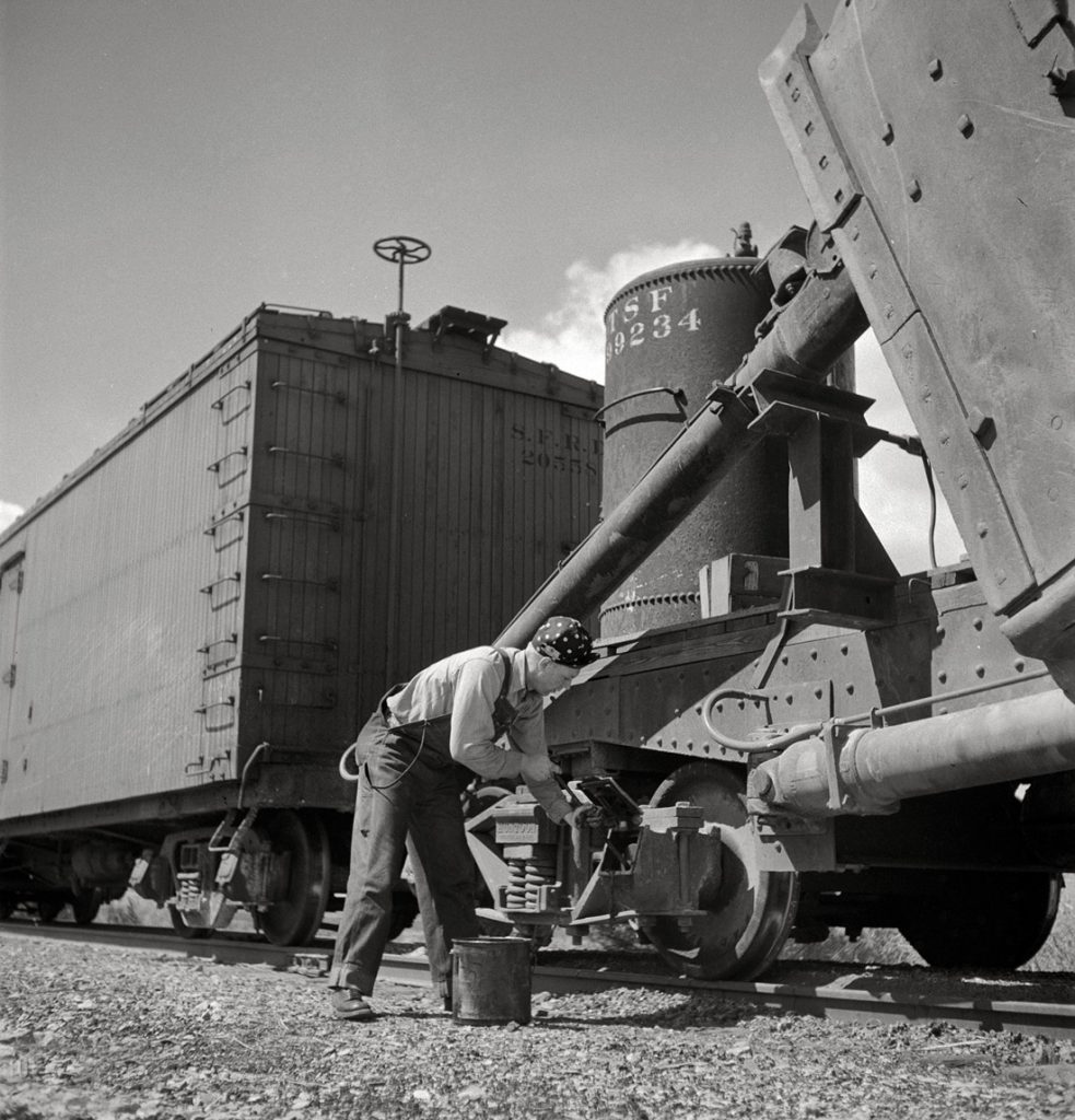 Guardafrenos R.E. Capsey trabajando mientras el tren de la linea de ferrocarril Atchison, Topeka y Santa Fe espera en un apartadero. Acomita, Nuevo Mexico. EEUU. 1943