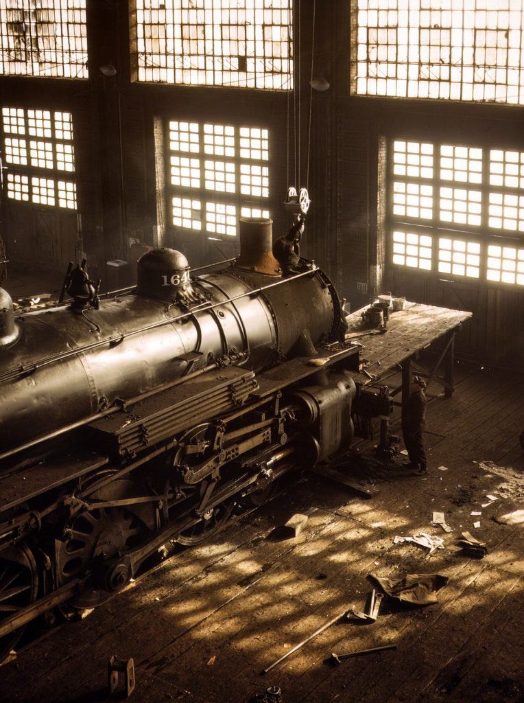Hombre trabajando en una locomotora en 40th Street Shops, Línea de ferrocarril del Noroeste de Chicago. EEUU. 1942