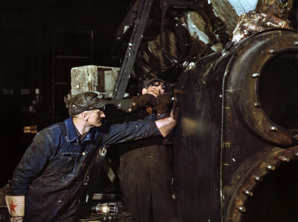 Trabajador en un cilindro de una locomotora en la línea de ferrocarril del Noroeste de Chicago. Illinois, Chicago. EEUU. 1942