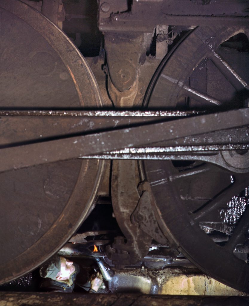Trabajador inspeccionando una locomotora en un foso de la casa de máquinas. Patio de proviso. Línea de ferrocarril del Noroeste de Chicago. EEUU. 1942